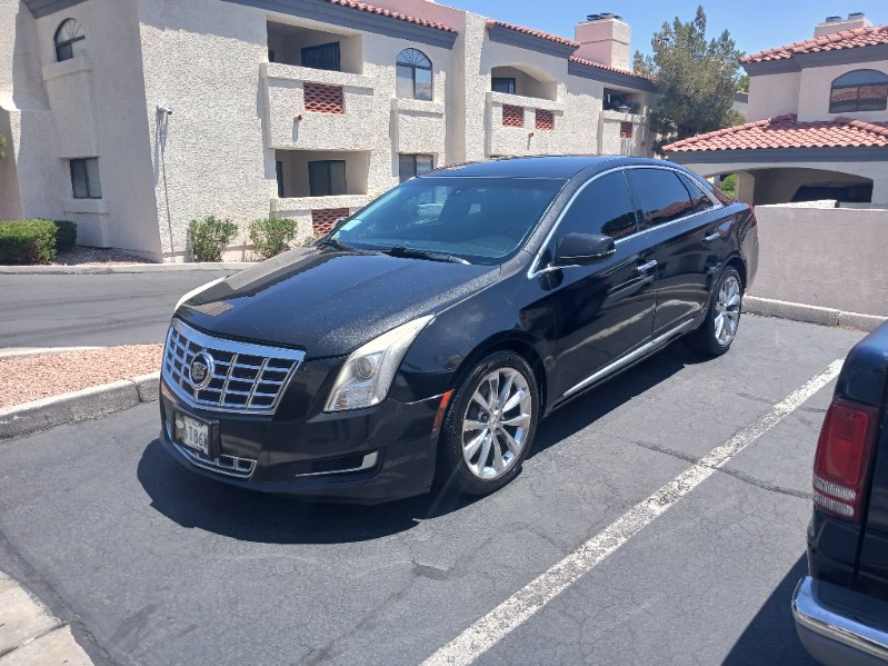 Clean black Cadillac XTS sedan parked in front of an apartment building